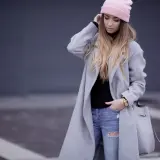 Modna dziewczyna w różowej czapce i szarym płaszczu, z podartymi jeansami. Stylowe stylizacje z szarym płaszczem na co dzień.
